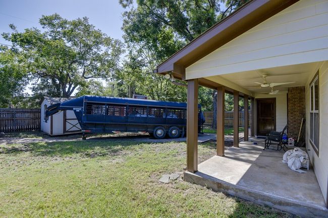 Fenced backyard featuring a ceiling fan, a storage unit, and a patio | Image 26