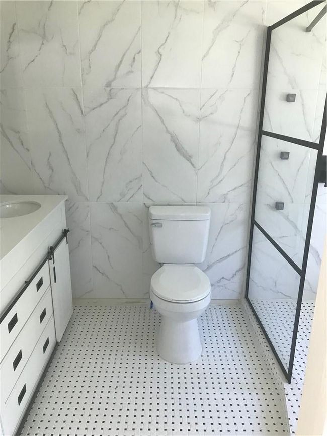 Bathroom with a shower, tile walls, toilet, and vanity | Image 23