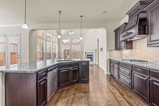 Kitchen with appliances with stainless steel finishes, a ceiling fan, a sink, a fireplace, and arched walkways | Image 11