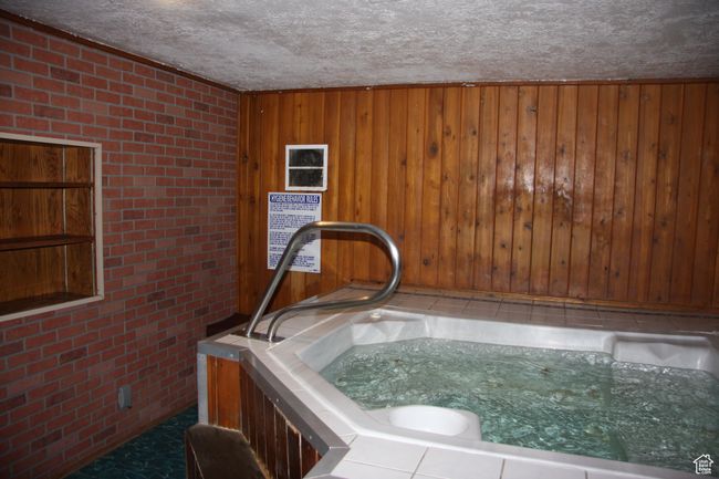 Detailed view of brick wall, a textured ceiling, wood walls, and a hot tub | Image 5