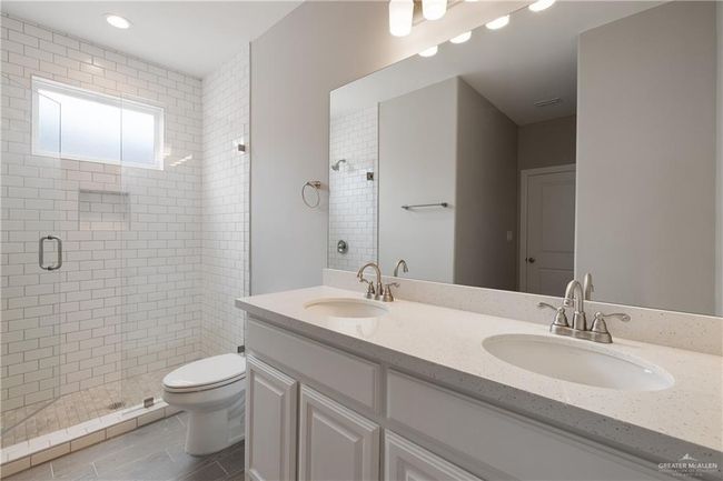 Bathroom featuring a shower stall, toilet, and double vanity | Image 7