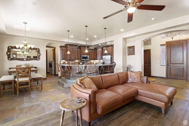 Living room featuring arched walkways, stone tile flooring, a chandelier, washer / dryer, and a ceiling fan | Image 37