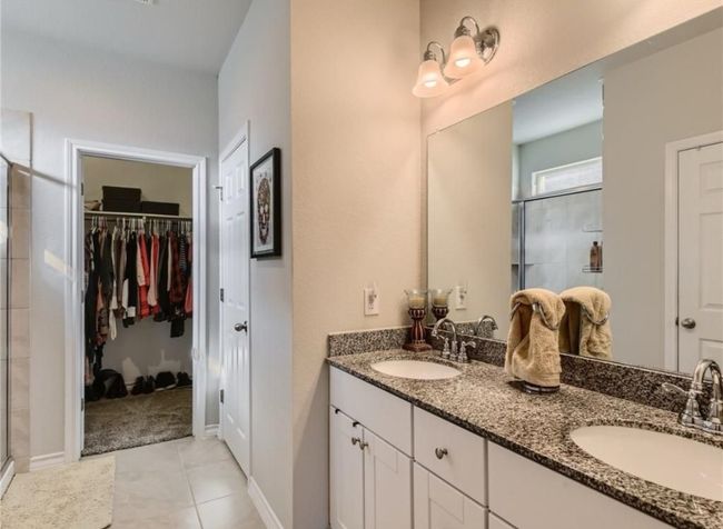 Full bath featuring a shower stall, double vanity, a spacious closet, and tile patterned flooring | Image 8