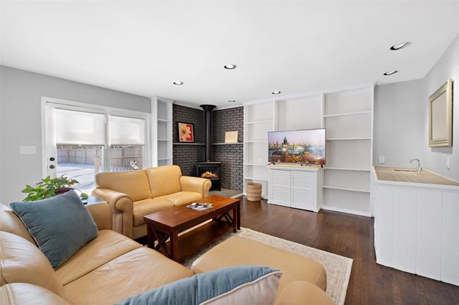 Living area with a wood stove, dark wood-style flooring, and recessed lighting | Image 18
