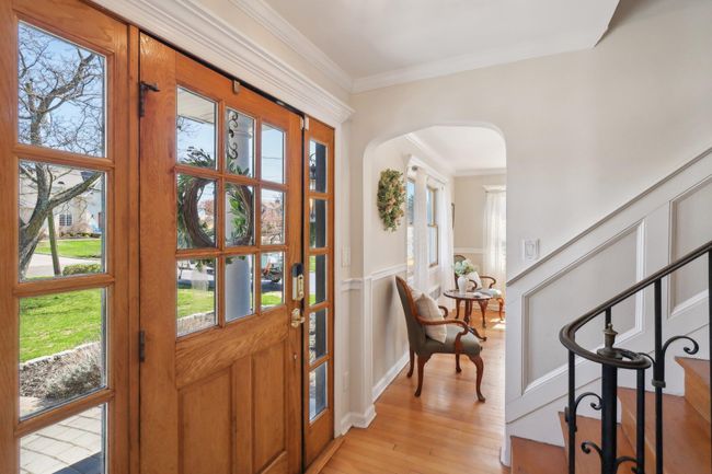 Entryway featuring arched walkways, a decorative wall, crown molding, wainscoting, and light wood-style flooring | Image 5