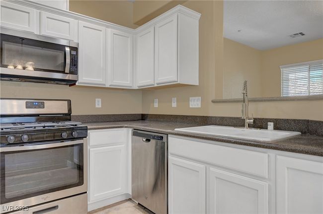 Kitchen featuring white cabinetry, a sink, dark countertops, and stainless steel appliances | Image 9