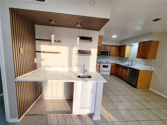 Kitchen featuring kitchen peninsula, sink, decorative light fixtures, and appliances with stainless steel finishes | Image 6
