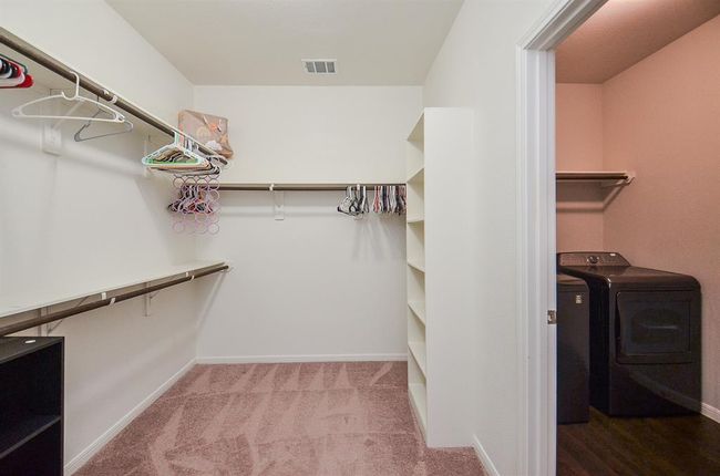 Wow! Built in shelving, tons of hanging rods and cushy carpeting fill the primary walk in closet, with what looks like a utility space (laundry appliances), right. | Image 18