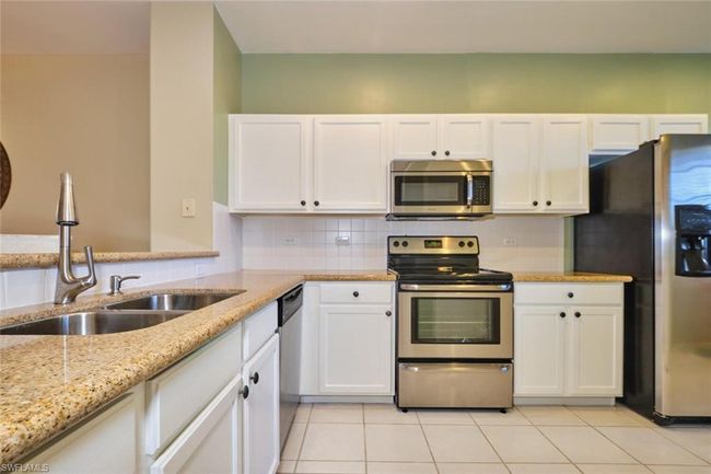 Kitchen featuring a sink, decorative backsplash, appliances with stainless steel finishes, and white cabinetry | Image 17