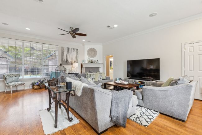 Living room with visible vents, crown molding, wood finished floors, and ceiling fan | Image 7