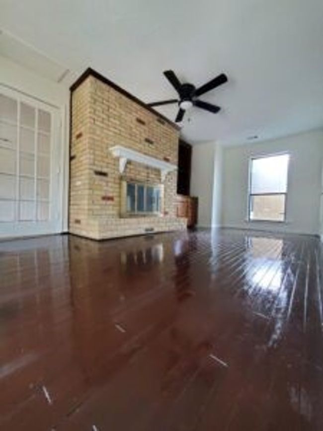 Unfurnished living room featuring ceiling fan, wood finished floors, and a fireplace | Image 38
