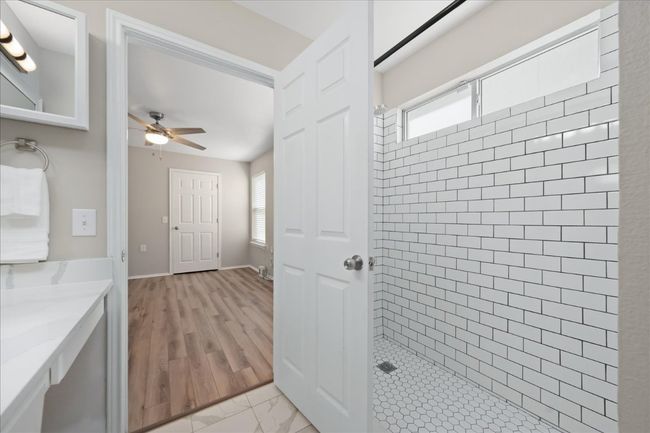 Bathroom with a wealth of natural light, ceiling fan, vanity, and a tile shower | Image 20