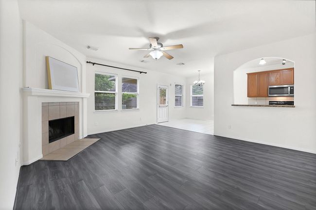 Spacious living room with updated flooring, cozy fireplace, and large windows. | Image 14