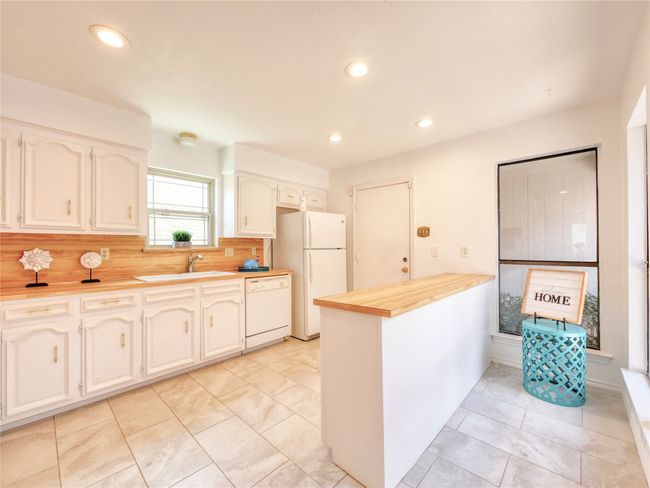 Kitchen with white appliances, a peninsula, recessed lighting, white cabinets, and backsplash | Image 13