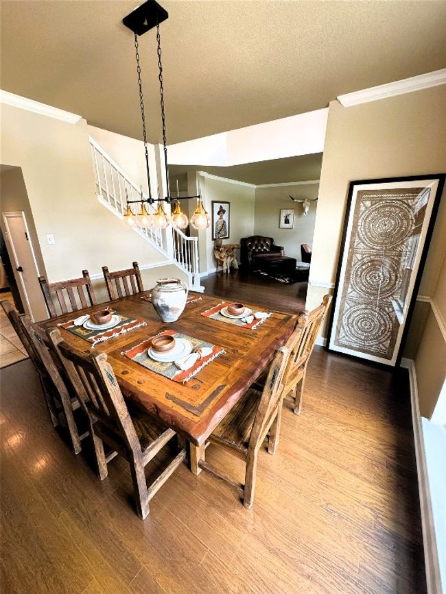 Dining area with crown molding, wood finished floors, and a chandelier. | Image 4