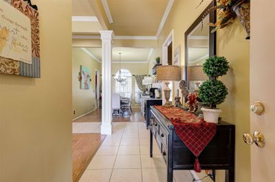 Corridor featuring crown molding, light hardwood / wood-style floors, an inviting chandelier, and ornate columns | Image 3