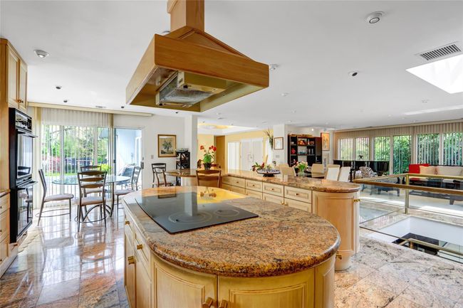 Kitchen featuring visible vents, a kitchen island, black appliances, open floor plan, and a skylight | Image 13