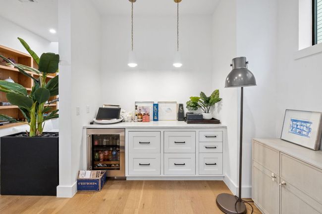 Indoor dry bar with beverage cooler and light wood finished floors | Image 19