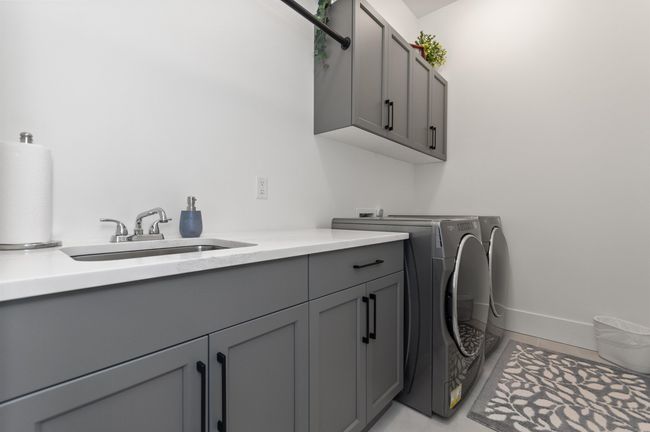 Laundry room featuring cabinet space, separate washer and dryer, light tile patterned flooring, and baseboards | Image 25