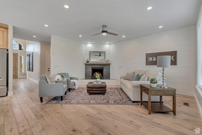 Living area with a ceiling fan, light wood finished floors, recessed lighting, and a tiled fireplace | Image 6