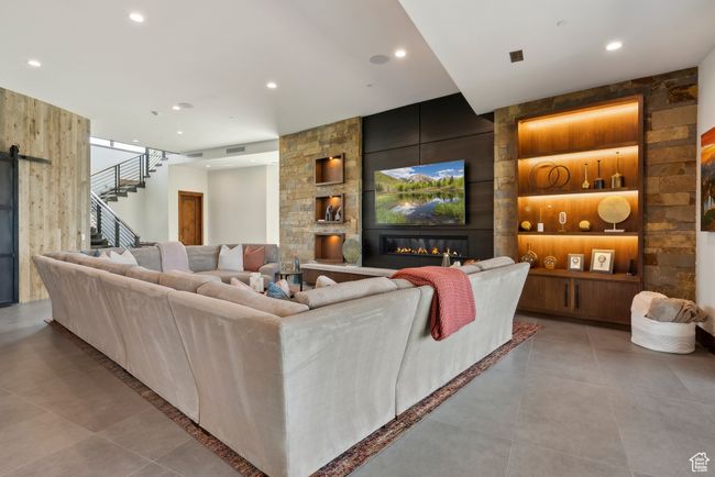 Living room with stairway, built in features, recessed lighting, a large fireplace, and tile patterned floors | Image 50