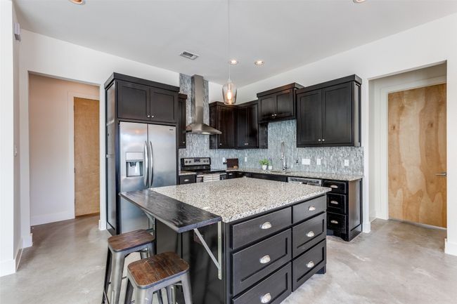 Kitchen with a kitchen bar, visible vents, decorative backsplash, appliances with stainless steel finishes, and wall chimney exhaust hood | Image 9
