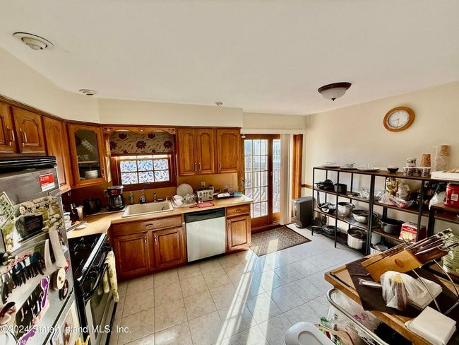 Kitchen featuring sink, light tile patterned floors, dishwasher, refrigerator, and gas range | Image 11