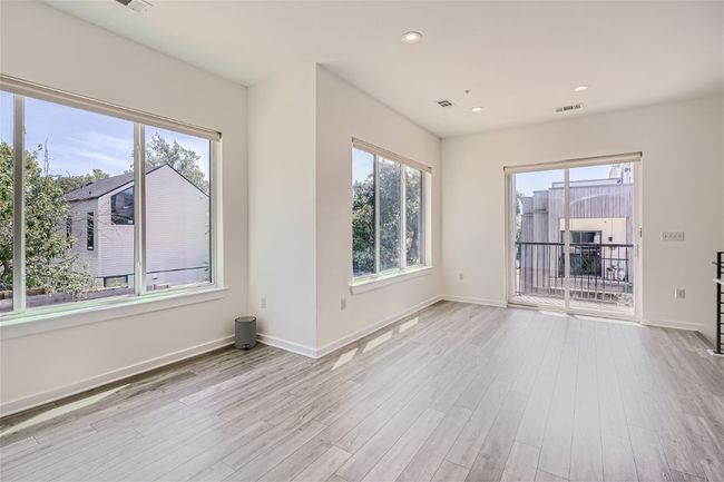 The open main floor layout is flooded with natural light from large windows, creating an inviting and airy ambiance. | Image 17