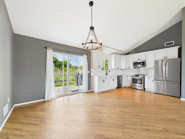 Kitchen with stainless steel appliances, a chandelier, vaulted ceiling, light countertops, and tasteful backsplash | Image 4