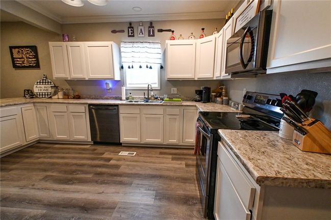 Kitchen featuring electric range, black microwave, dishwashing machine, a sink, and crown molding | Image 12