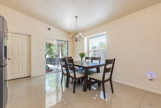 Dining space with healthy amount of natural light, a chandelier, lofted ceiling, baseboards, and light tile patterned floors | Image 9