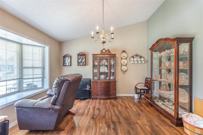 Office featuring vaulted ceiling, a chandelier, wood finished floors, baseboards, and a textured ceiling | Image 11