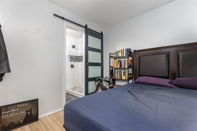Bedroom featuring a barn door, hardwood / wood-style flooring, and ensuite bath | Image 15