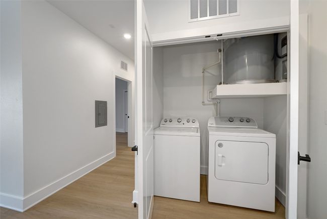 Washroom with electric panel, washing machine and dryer, light wood-style floors, baseboards, and recessed lighting | Image 15