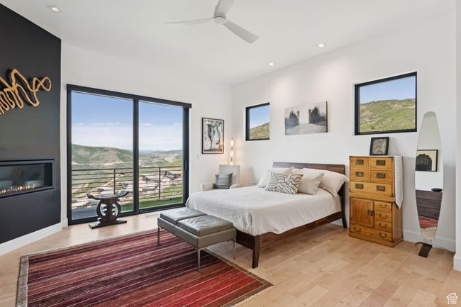 Bedroom featuring light wood-type flooring, access to outside, recessed lighting, a glass covered fireplace, and ceiling fan | Image 22