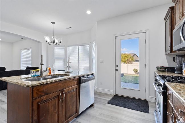 Kitchen with stainless steel appliances, a center island with sink, sink, hanging light fixtures, and light wood-type flooring | Image 10