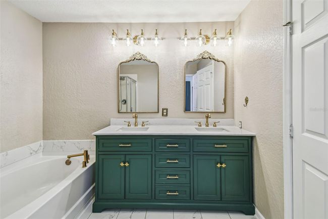 Upstairs primary bedroom features an en-suite, updated bathroom complete with a double vanity, garden tub, walk-in shower, and a private toilet closet. | Image 18