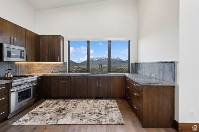 Kitchen with stainless steel appliances, a high ceiling, a mountain view, a sink, and decorative backsplash | Image 90