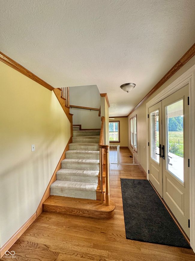 entrance foyer featuring wood finished floors, french doors, ornamental molding, baseboards, and stairway | Image 50