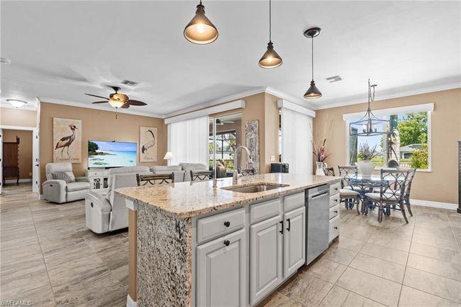 Kitchen with a sink, dishwasher, a center island with sink, a ceiling fan, and ornamental molding | Image 20