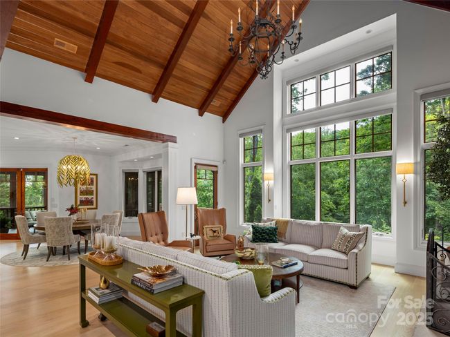 Soaring windows in main level living room allow in abundant light and show the lush and private landscaping. Windows have motorized blinds with remote for light control. | Image 8
