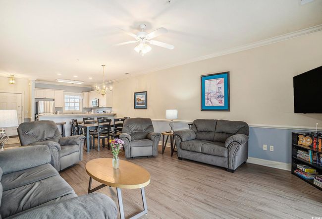 Living room featuring ornamental molding, a chandelier, light wood-type flooring, ceiling fan, and baseboards | Image 4