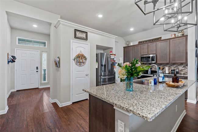 Kitchen with appliances with stainless steel finishes, a sink, dark brown cabinetry, light stone countertops, and recessed lighting | Image 11