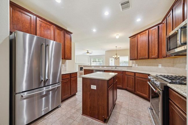 The well-appointed kitchen boasts modern UPGRADED SS Kitchen Aid appliances including a French door 20 cubic ft refrigerator with a bottom drawer freezer and a cook's dream - a 5-burner gas range and convection oven. | Image 13