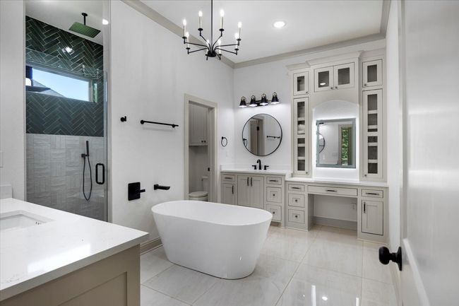 Bathroom with a shower stall, two vanities, a freestanding bath, ornamental molding, and a chandelier | Image 19