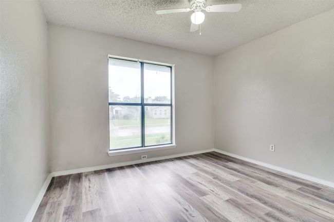 Spare room with a textured ceiling, ceiling fan, and wood finished floors | Image 15