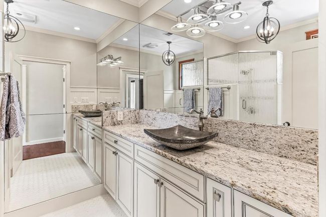Full bathroom featuring ornamental molding, a chandelier, a stall shower, double vanity, and a decorative wall | Image 22