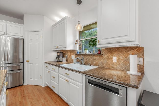 Kitchen with stainless steel appliances, white cabinetry, and decorative backsplash | Image 13