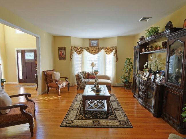 Living area featuring light wood-type flooring, baseboards, a baseboard heating unit, and visible vents | Image 17