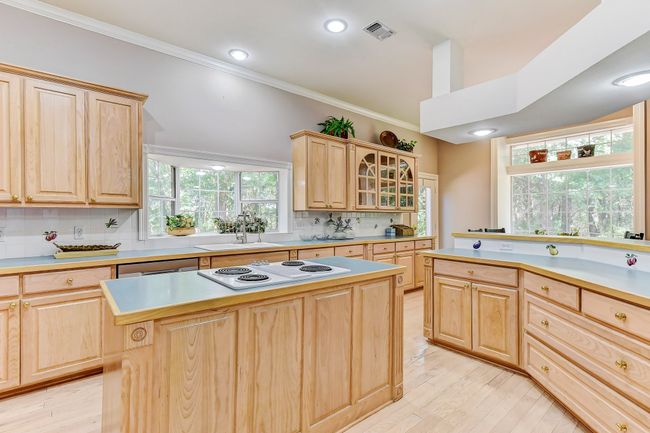 Kitchen featuring light countertops, visible vents, light brown cabinets, a sink, and decorative backsplash | Image 12